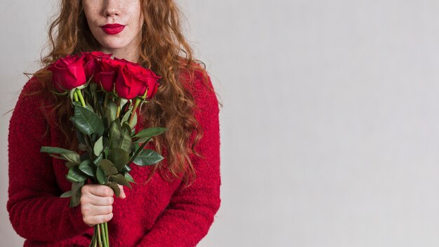 Schöne Frau, die einen Blumenstrauß der Rosen anhält