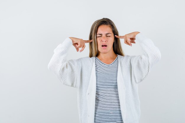 Schöne Frau, die Finger auf Kopf in Jacke hält und nachdenklich aussieht. Vorderansicht.