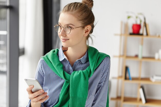 Schöne Frau, die formell im Büro mit Telefon gekleidet ist