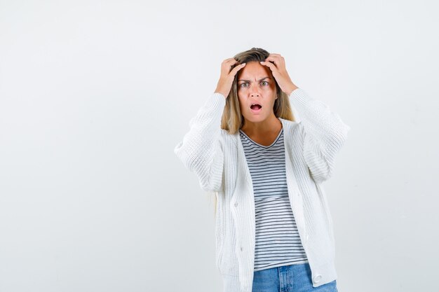 Kostenloses Foto schöne frau, die hände zum kopf in der jacke erhebt und beunruhigend aussieht. vorderansicht.