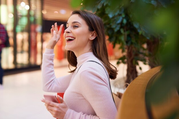 Schöne Frau, die Hallo sagt und mit der Hand winkt