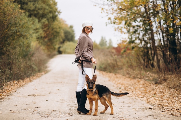 Schöne Frau, die heraus ihren Hund im Herbstpark geht