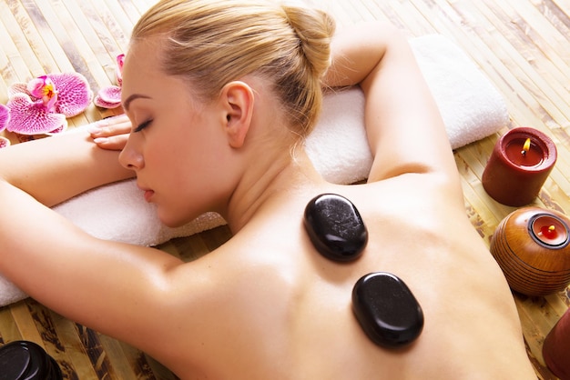 Kostenloses Foto schöne frau, die im spa-salon mit heißen steinen auf körper entspannt. schönheitstherapie