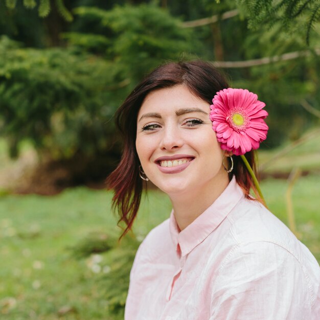 Schöne Frau, die mit Blume im Haar lächelt