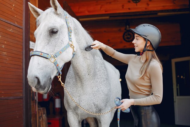 Schöne Frau, die mit einem Pferd steht