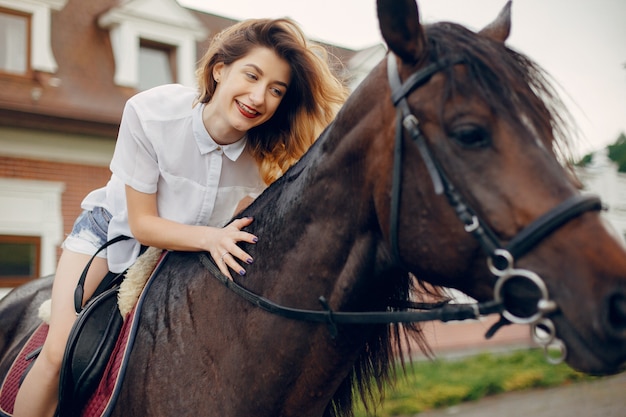 Schöne Frau, die mit einem Pferd steht