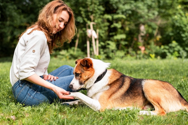 Schöne Frau, die mit ihrem Hund im Park spielt