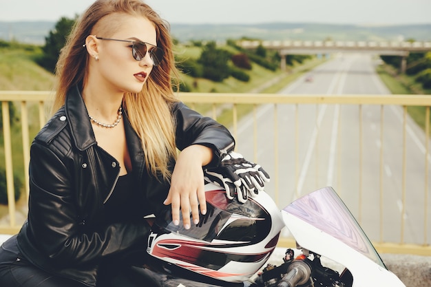 Schöne Frau, die mit Sonnenbrillen auf einem Motorrad aufwirft