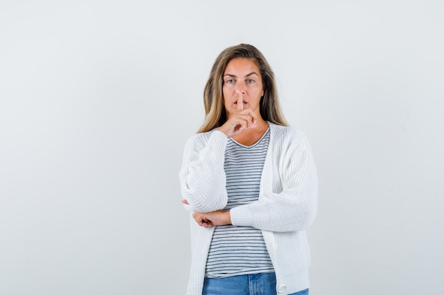 Schöne Frau, die Stille Geste in Jacke zeigt und ruhige Vorderansicht schaut.