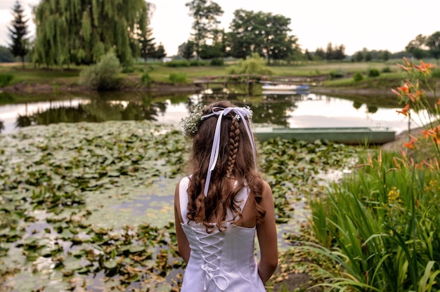 Schöne Frau, die vor einem Teich im schönen Garten steht