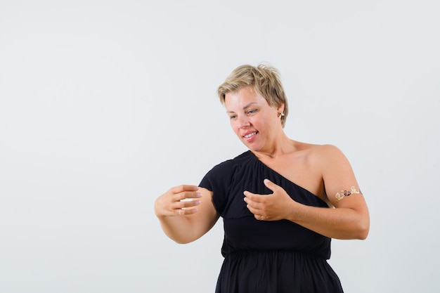 Schöne Frau, die wie schauendes Telefon in der schwarzen Bluse aufwirft