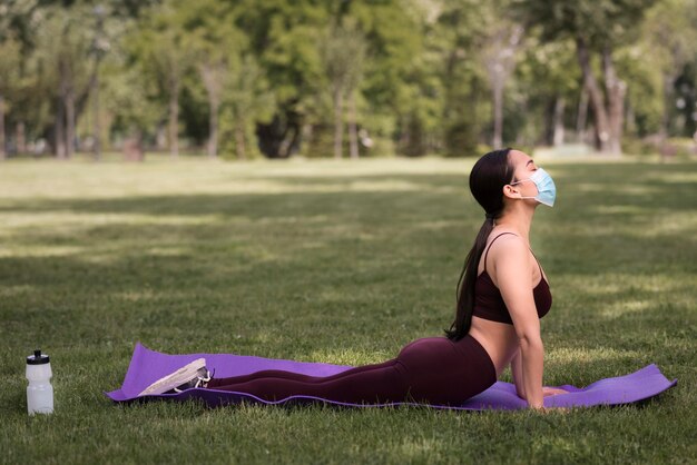 Schöne Frau, die Yoga draußen praktiziert