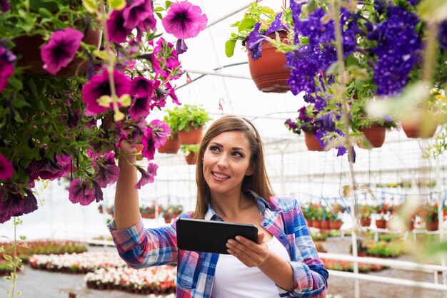 Schöne Frau Floristin mit Tablet-Computer im Gartencenter Gewächshaus Überprüfung Blumen Verkauf