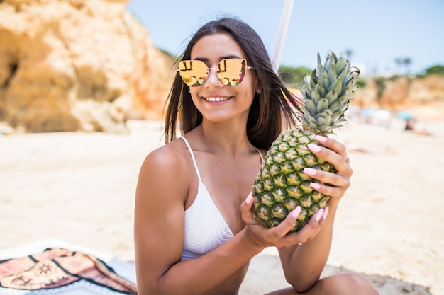 Schöne Frau hält Ananasfrucht am Strand