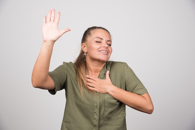 Schöne Frau im grünen Outfit, die glücklich ihre Hand zeigt.