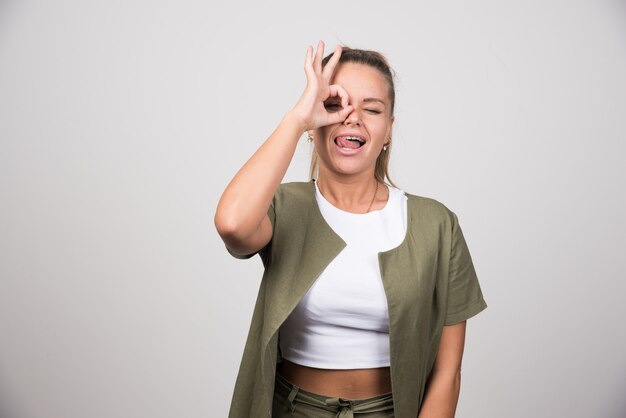 Schöne Frau im grünen Outfit, die ihre Zunge herausstreckt.