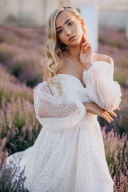 Schöne Frau im Hochzeitskleid im Lavendelfeld