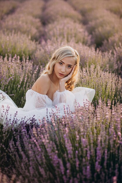 Schöne Frau im Hochzeitskleid im Lavendelfeld