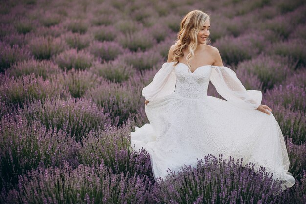 Schöne Frau im Hochzeitskleid im Lavendelfeld