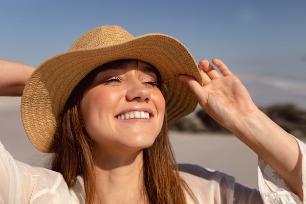 Schöne Frau im Hut, der weg auf Strand im Sonnenschein schaut