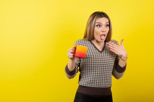 Schöne Frau im lässigen Outfit mit einer Tasse Tee angewidert.