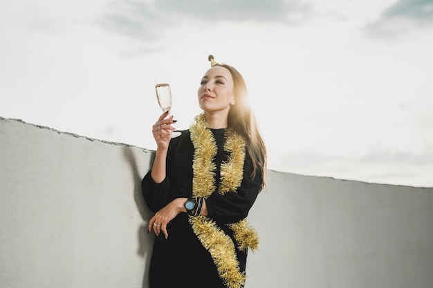 Schöne Frau im schwarzen Kleid, das ein Glas Champagner anhält