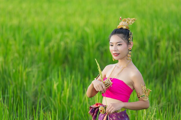 Schöne Frau im thailändischen traditionellen Outfit lächelnd und stehend am Tempel