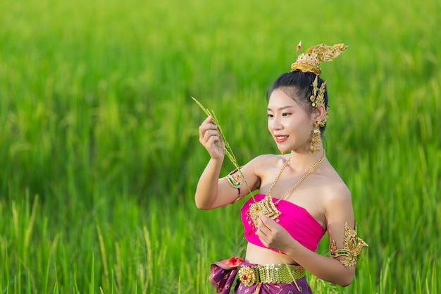 Schöne Frau im thailändischen traditionellen Outfit lächelnd und stehend am Tempel