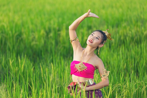 Schöne Frau im thailändischen traditionellen Outfit lächelnd und stehend am Tempel