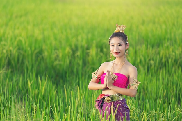 Schöne Frau im thailändischen traditionellen Outfit lächelnd und stehend am Tempel