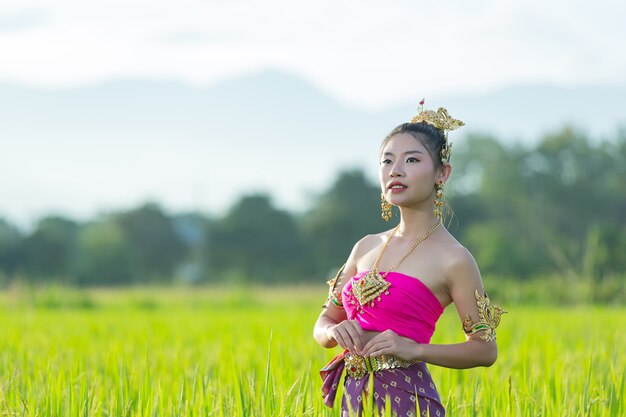 Schöne Frau im thailändischen traditionellen Outfit lächelnd und stehend am Tempel