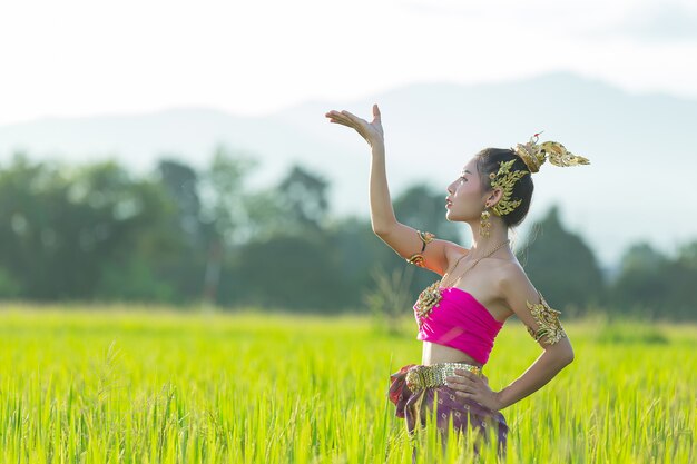 Schöne Frau im thailändischen traditionellen Outfit lächelnd und stehend am Tempel