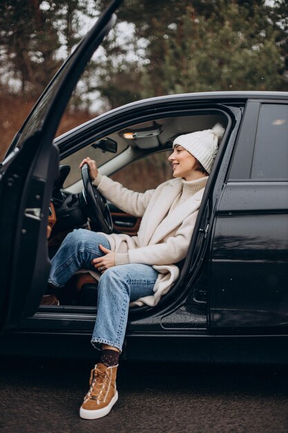 Schöne Frau im Wintermantel, die im Auto sitzt