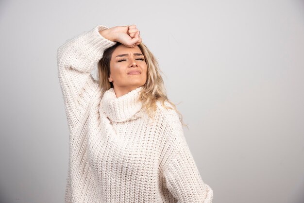 Schöne Frau im Winteroutfit, das auf grauem Hintergrund schläft.