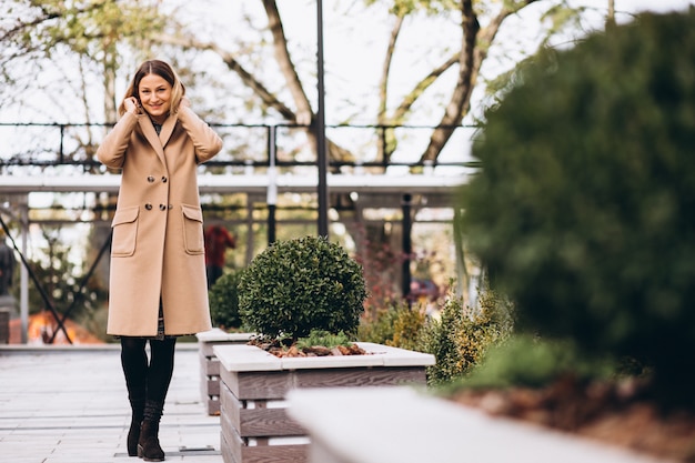 Schöne Frau in einem beige Mantel draußen im Park