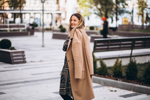 Schöne Frau in einem beige Mantel draußen im Park