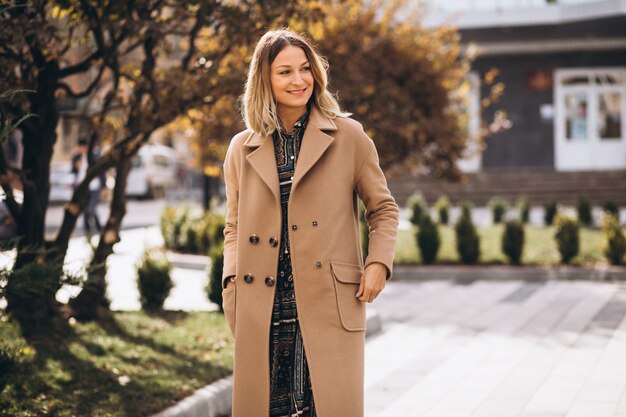 Schöne Frau in einem beige Mantel draußen im Park