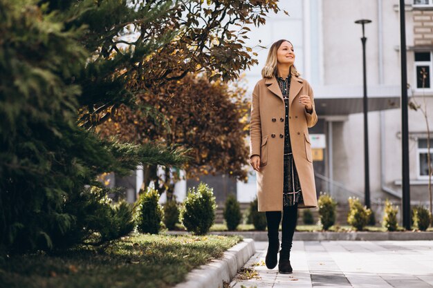 Schöne Frau in einem beige Mantel draußen im Park