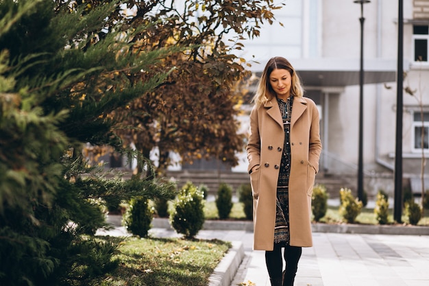 Schöne Frau in einem beige Mantel draußen im Park