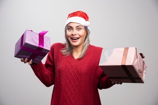 Schöne Frau in Santa Hut posiert mit Weihnachtsgeschenken.