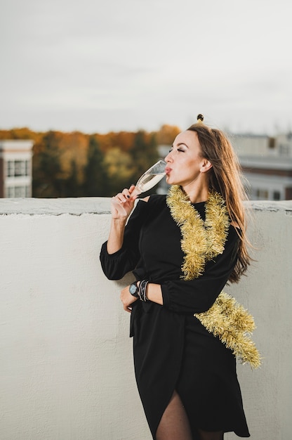 Schöne Frau in trinkendem Champagner des schwarzen Kleides