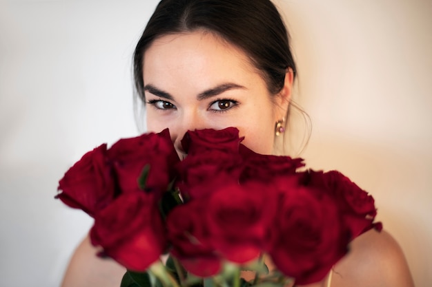 Schöne Frau lächelt und hält Valentinstag Strauß roter Rosen