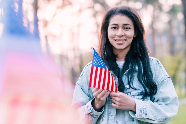 Schöne Frau mit amerikanischer Flagge der Andenkens draußen