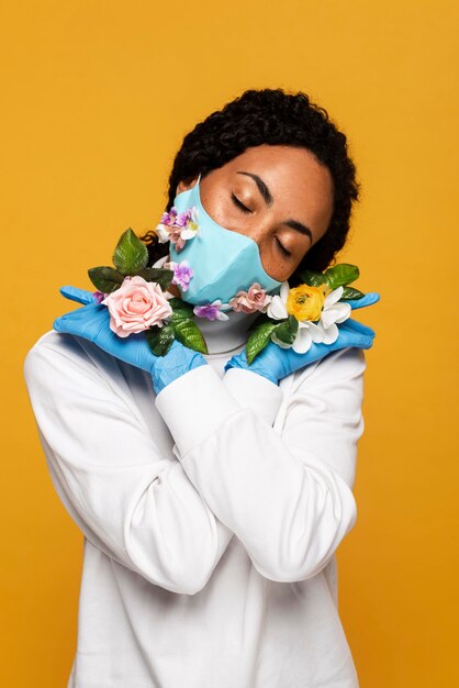 Schöne Frau mit Blumenhandschuhen und Maske