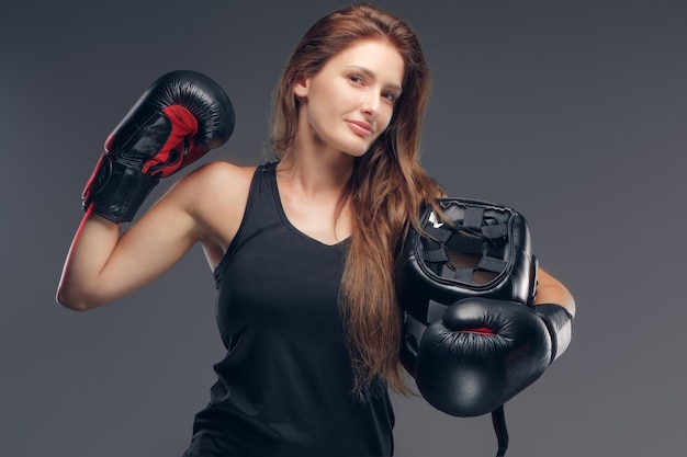 Schöne Frau mit Boxerhandschuhen hält Schutzhelm, während sie für Fotografen posiert.