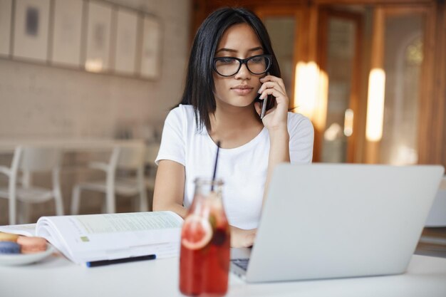 Schöne Frau mit Brille studiert im Café und wählt die Nummer aus