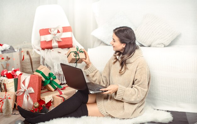 Schöne Frau mit Computer und Weihnachtsgeschenken.