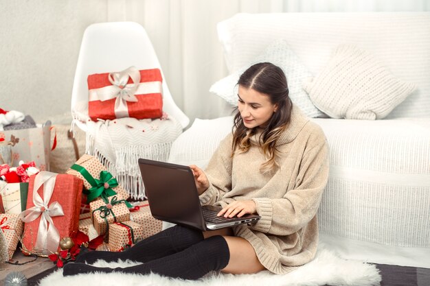 Schöne Frau mit Computer und Weihnachtsgeschenken.