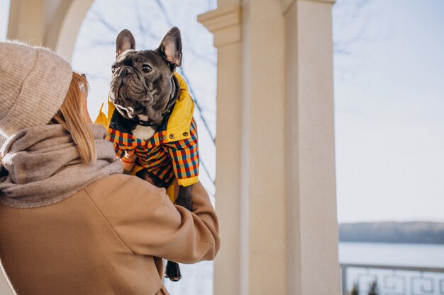 Schöne Frau mit französischer Bulldogge gehend in Park