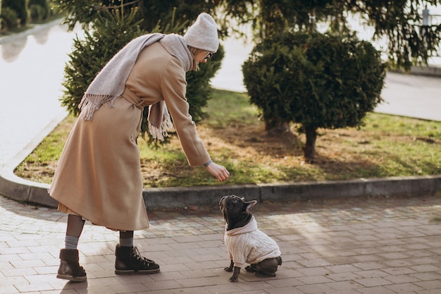 Schöne Frau mit französischer Bulldogge gehend in Park